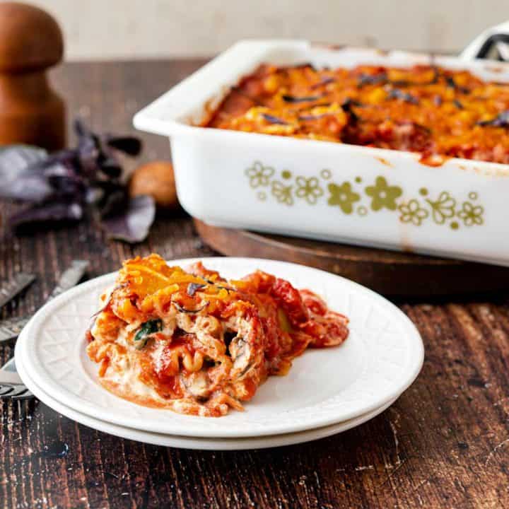 White plate with a lasagna roll on it, with casserole dish in background