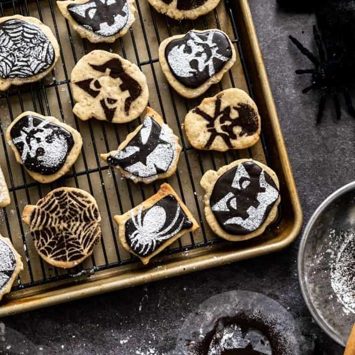 Baking sheet and cooling tray with halloween-stenciled shortbread cookies on it
