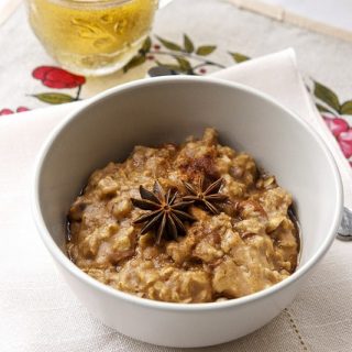 Close up shot of a bowl of almond chai oatmeal, on a linen with cup of tea