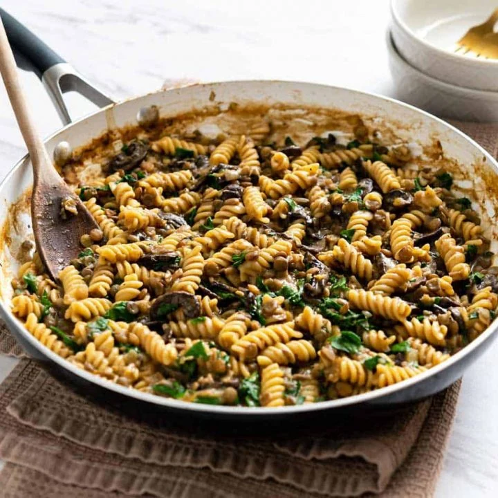 Image of one-pot lentil mushroom pasta in a large pan sitting on a towel