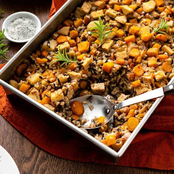 Large baking pan of squash wild rice bake on a brown wood table with rust-colored linen