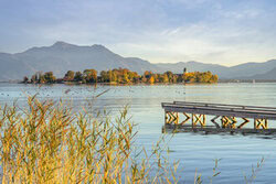 Beautiful view of Lake Chiemsee featuring Fraueninsel at sunset with soft clouds.