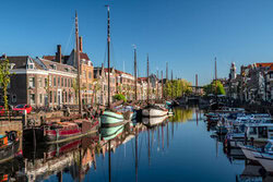 Harbor view of Delfshaven in Rotterdam featuring a sailing boat and calm water reflection