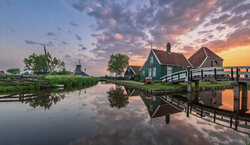 Sunrise over windmills in Holland with calm reflection in the water