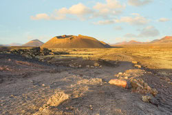 Path to El Cuervo volcano on Lanzarote with rugged terrain and soft clouds