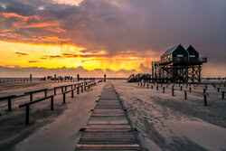 Wall art: Sunset at the North Sea with gentle waves and wooden jetties.