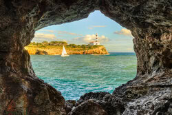 Blick durch einen Felsbogen auf das ruhige Meer von Portocolom auf Mallorca