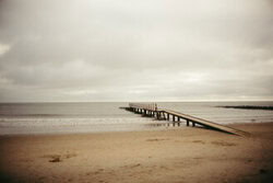 Calm beach with a jetty leading into the Baltic Sea, gentle waves and golden sand.