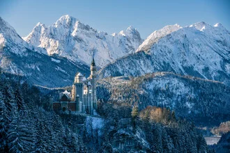 Verschneite Winterlandschaft in Bayern mit sanften Hügeln und einem Schloss im Hintergrund