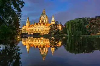 Evening atmosphere at the New Town Hall in Hanover with soft lights and a calm pond
