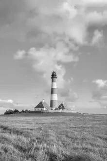 Black and white photo art: Westerheversand lighthouse by the North Sea with wide meadows