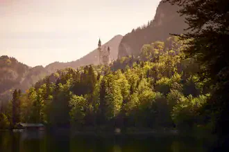 Photo art by Norbert Gräf: View from Alpsee towards Neuschwanstein Castle under sunlight.
