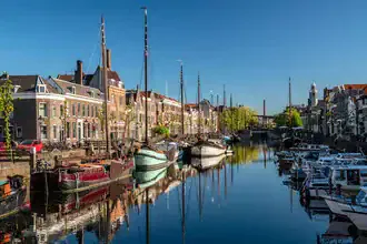 Harbor view of Delfshaven in Rotterdam featuring a sailing boat and calm water reflection