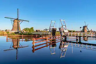 Photo art by Achim Thomae: Windmills in Kinderdijk with calm water reflection.