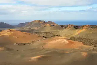 Vulkanlandschaft im Timanfaya Nationalpark auf Lanzarote mit sanften Hügeln und warmen Farbtönen.