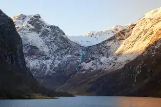 Photo art by Norbert Gräf: Nærøyfjord at sunset with warm evening glow and gentle waves.