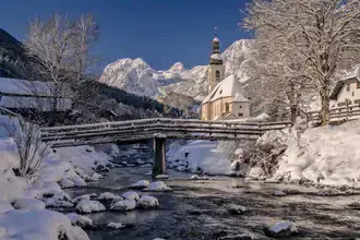 Winter landscape with snow-covered mountains and a church in Upper Bavaria