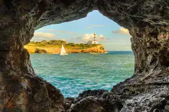Blick durch einen Felsbogen auf das ruhige Meer von Portocolom auf Mallorca