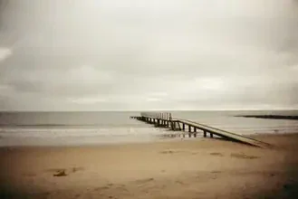 Calm beach with a jetty leading into the Baltic Sea, gentle waves and golden sand.