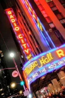 Neon lights of Radio City Music Hall at night, glowing and inviting.