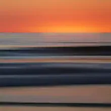Photo art by Steffi Louis: gentle waves at the shore with a calm sunset.