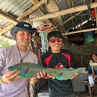 Two men holding a colorful fish during a fishing trip in the Philippines.