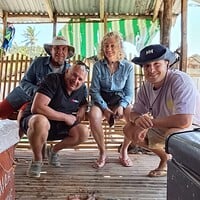 Enjoying fresh seafood and good company during a Philippines island trip. Exploring local seafood with happy travelers in a rustic Filipino hut.