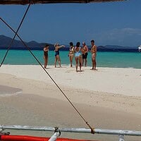 Group of tourists enjoying a sunny day on a pristine beach in the Philippines. Relaxing beach scene with travelers in the Philippines.