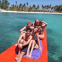 A family relaxing on a boat at a tropical Philippine beach with clear turquoise waters and palm trees in the background. Beautiful family enjoying island beach in the Philippines.