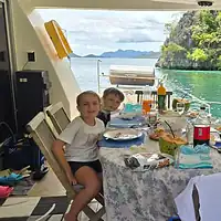 Family dining on a boat with stunning island scenery in the Philippines. Enjoying a family meal on a boat with scenic island views in the Philippines.