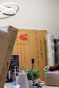 Detailed alt text showing a woman preparing a package in a modern kitchen.