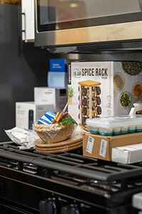 Spice rack, children's books, snacks on kitchen counter for home organization and kitchen decor.