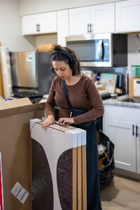 Woman unpacking furniture with care in a modern kitchen setting.