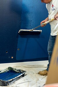 Painted deep blue wall using roller for a smooth finish.