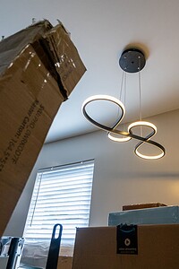 Bright modern LED ceiling light with unique circular design illuminating a room filled with moving boxes.