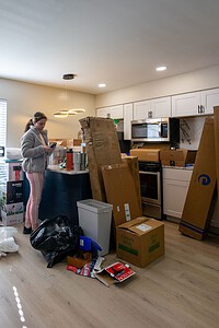Cute girl packing kitchen area with boxes and unpacked items during moving process.