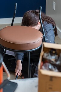 Disoriented individual kneeling among boxes and objects, overwhelmed by disorganization.