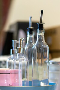 Glass bottles with pumps and droppers, used for skincare or essential oils, on a tray with a soft-focus background.