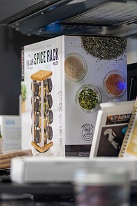 Spice rack and ingredients on stove top, organized kitchen essentials for cooking convenience.