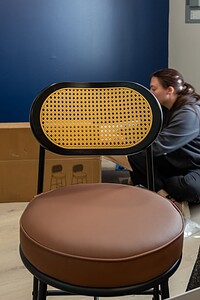Stylish beige and black chair being assembled with boxes and tools around.