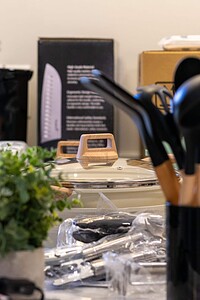 High-quality kitchen utensils, glass bottles, and cooking tools on a cluttered countertop.