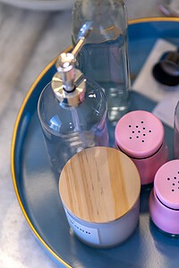 Stylish condiment tray featuring glass bottles and pink salt and pepper shakers for dining.