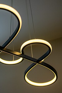 Stylish modern LED light fixture with illuminated black and gold rings, ideal for contemporary interior decor.