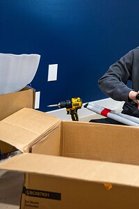 High-quality image of a handyman using a power drill to assemble furniture in an office.