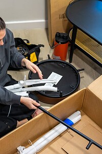 Alt text: Woman assembling emergency rescue equipment with pipes and tools on the floor.