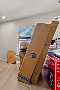 Bright living space with a vibrant blue accent wall, packed boxes, and natural light from the window.
