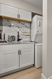 Bright kitchen with laundry appliances, minimalist design, and light wood flooring.