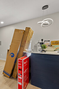 Interior of a newly renovated room with blue accent wall, moving boxes, and modern chandelier lighting.
