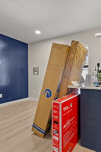 Interior renovation scene with boxed appliances, moving boxes, and a partially decorated room.
