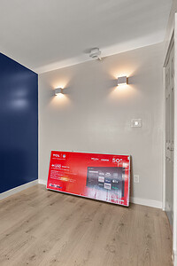 Bright contemporary interior with a striking blue wall, new TV, and moving boxes, perfect for showcasing home renovation or staging.